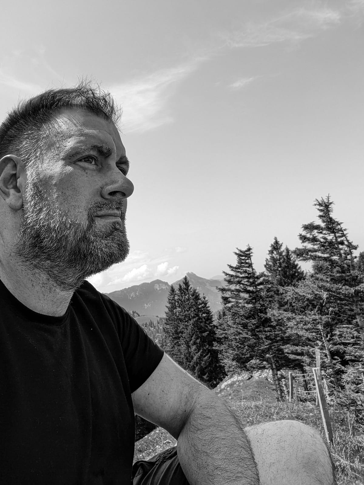 Schwarzweiß-Portrait von Sebastian Theiler in bergiger Landschaft.